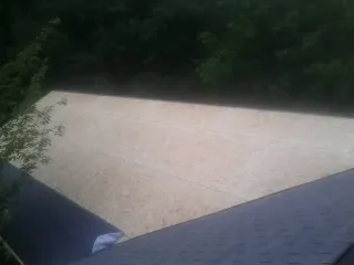 New OSB roof sheathing installed beside an existing shingle roof in Carthage